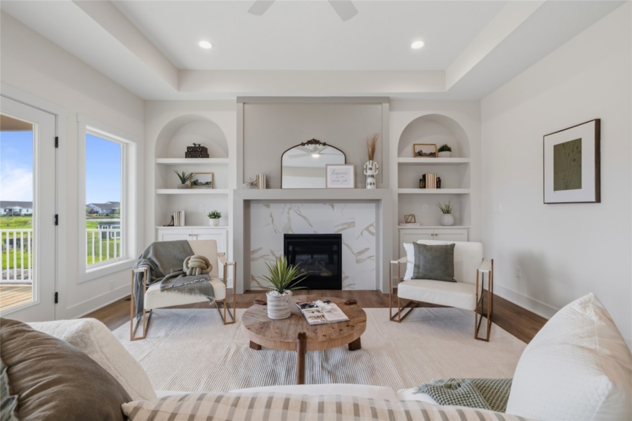 Symmetrical living room with marble fireplace, dual arched built-in bookshelves, and French doors in Ankeny Iowa new construction