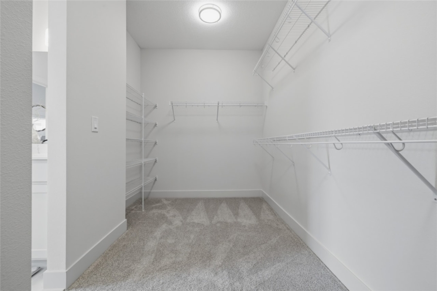 Spacious walk-in closet with white wire shelving and carpet flooring in Ankeny Iowa new home