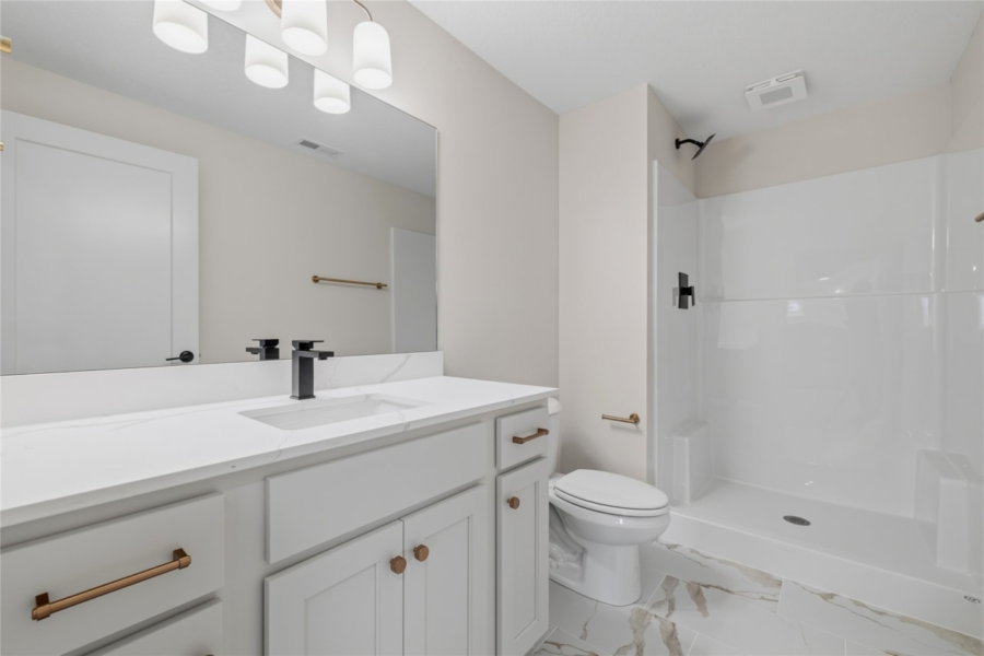 Secondary bathroom with white shaker vanity, quartz countertop, matte black faucet, and marble-look tile floor in Ankeny Iowa new construction home