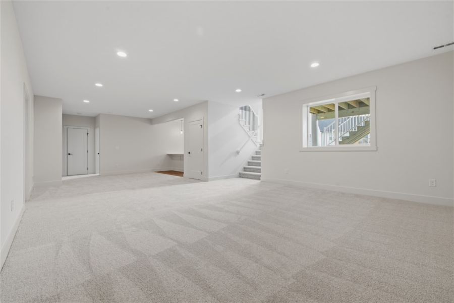 Open finished walkout basement with carpet, staircase, recessed lighting, and window in Ankeny Iowa new home