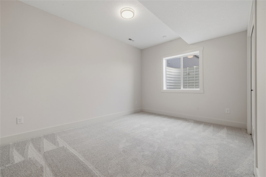 Empty lower level bedroom with carpet flooring and window in Ankeny Iowa new build