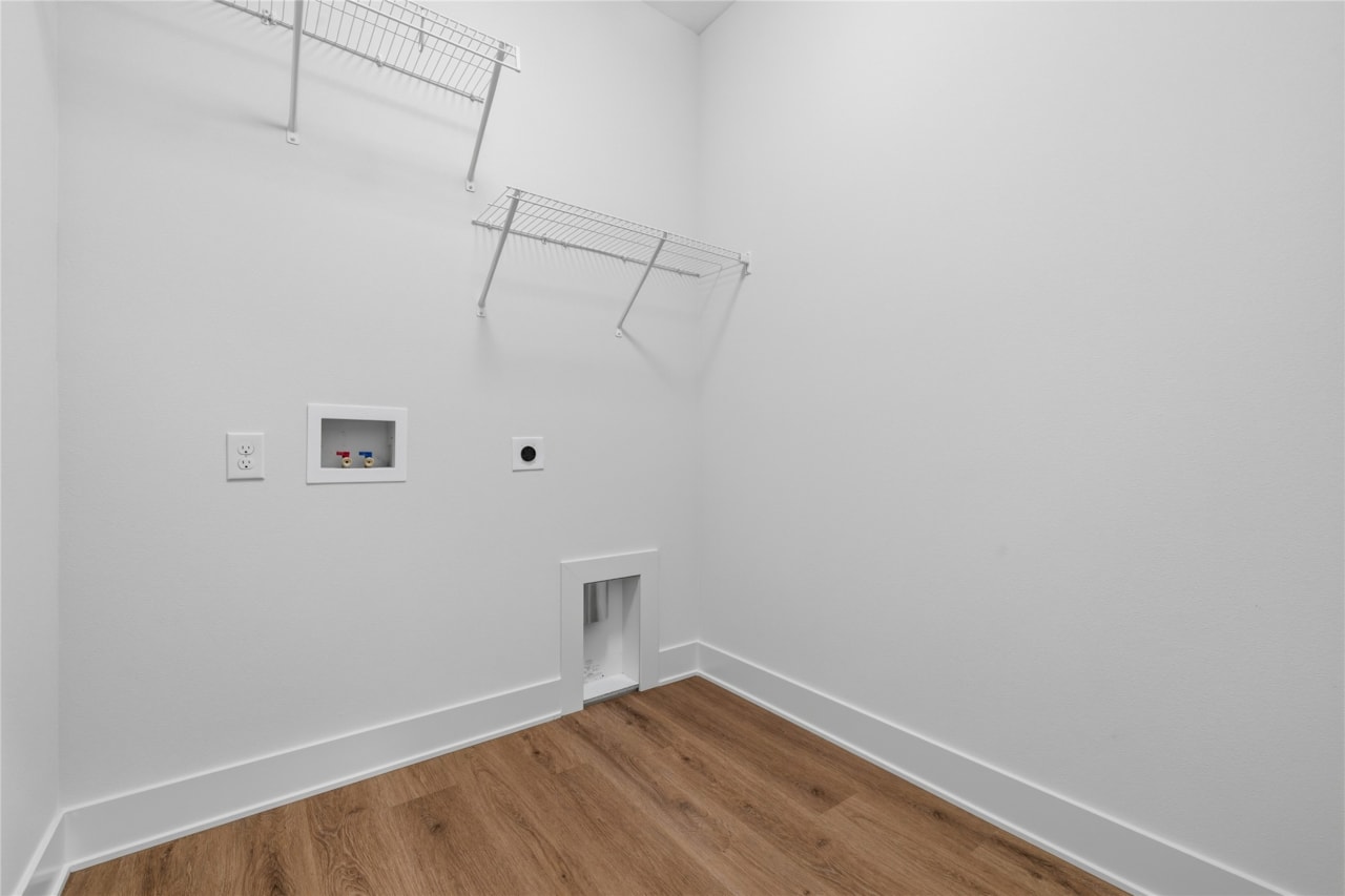 Main level laundry room with wire shelving, washer dryer hookups, and LVP flooring in Ankeny Iowa new construction