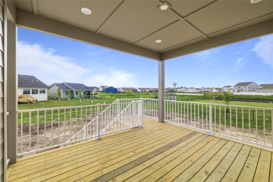 Covered elevated deck with recessed lighting, white railings, wood decking, and open neighborhood views in Ankeny Iowa new construction home