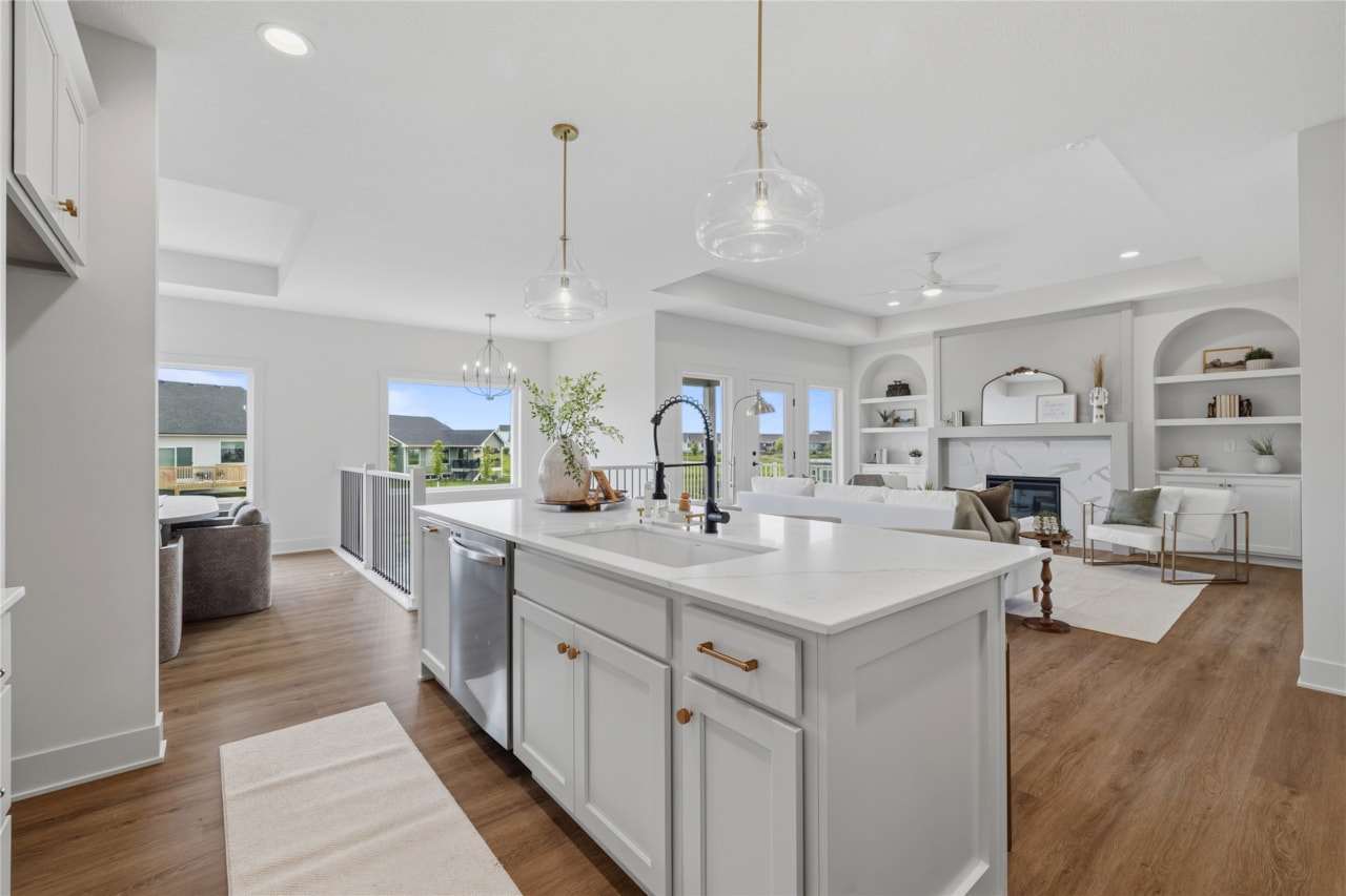 Gray kitchen island with gold hardware and open view to living room and deck in Ankeny Iowa new construction home