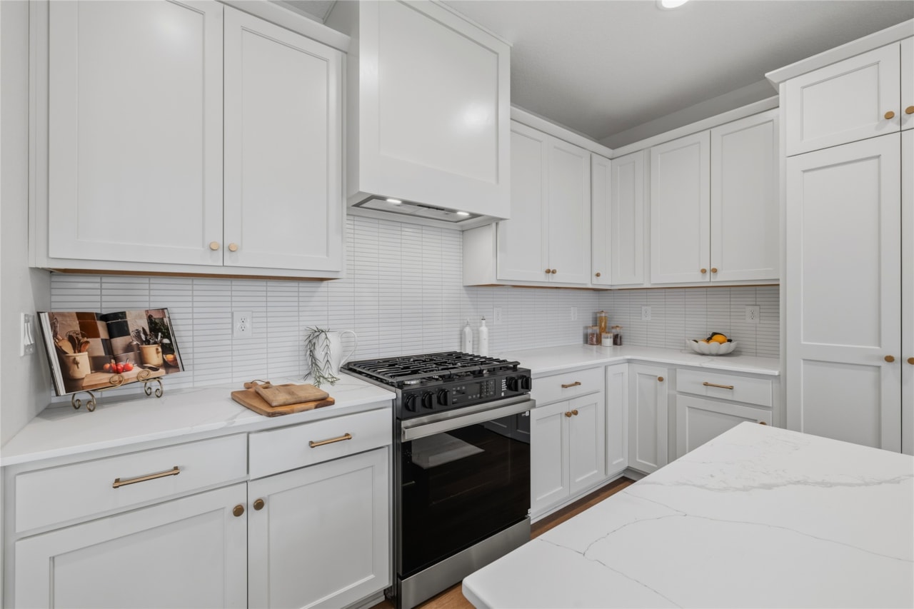 White shaker kitchen cabinets with gas range, tile backsplash, and quartz countertops in Ankeny Iowa new home