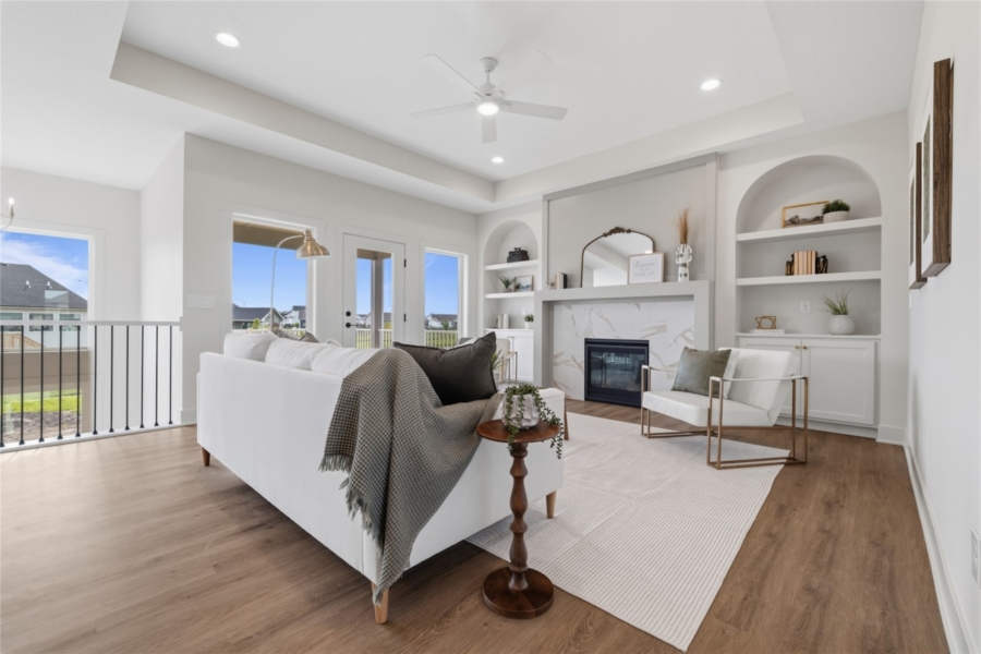 Bright living room with marble fireplace, arched built-in shelves, and French doors to deck in Ankeny Iowa new home