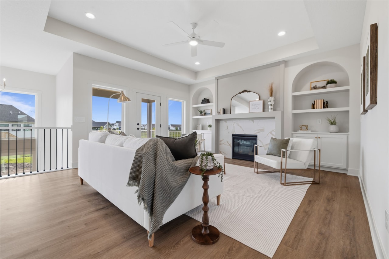 Bright living room with marble fireplace, arched built-in shelves, and French doors to deck in Ankeny Iowa new home